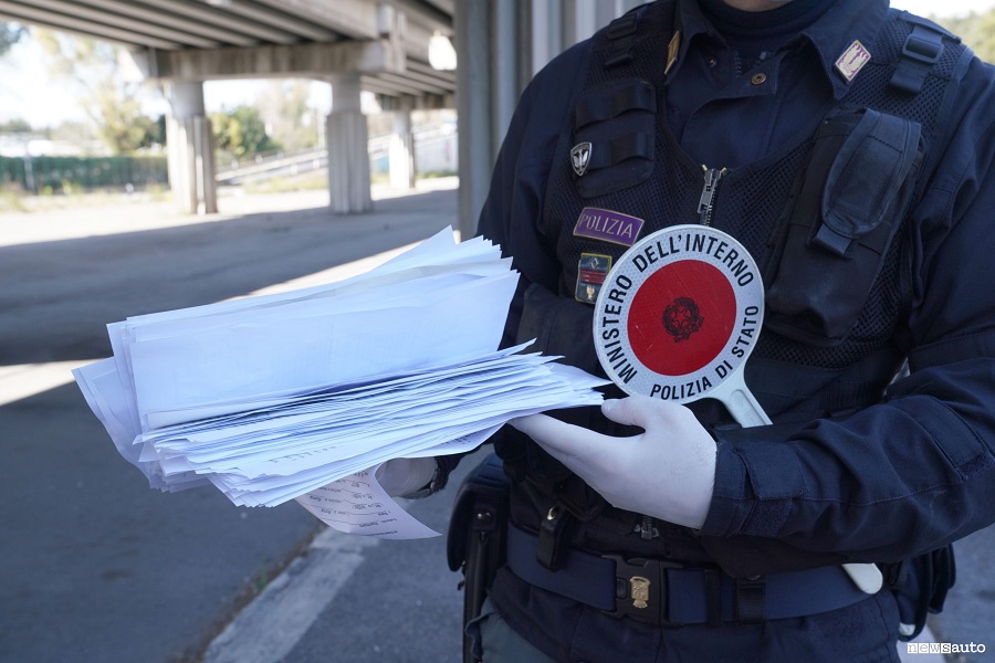 Un agente di Polizia con la paletta in mano mentre controlla la validità della polizza assicurativa  